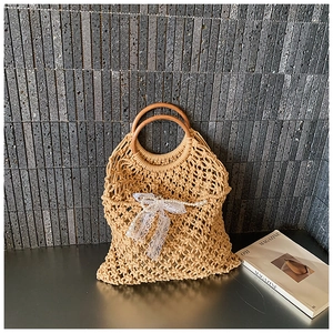 Detail of woven straw handbag featuring round wooden handles and lace pearl charm