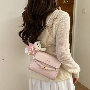 Rear view of a light pink shoulder bag featuring golden hardware and a cute teddy charm