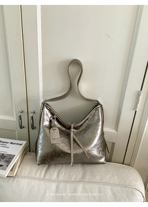 Detail of metallic silver hobo bag with unique pleated texture and fashion tag