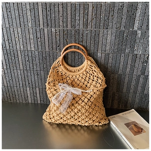 Detail of hand-woven hollow handbag featuring wooden round handles and lace bow decor