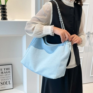Détail du sac hobo en jean bleu clair avec bandoulière chaîne argentée sur mannequin