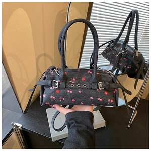 Detail of dark denim handbag with red floral patterns and silver metal buckle accent