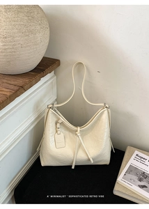 Detail of off-white large tote bag showing shiny wrinkled leather texture and fashion tag