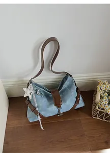 Detail of denim shoulder bag with leather strap and silver star pendant on wood floor