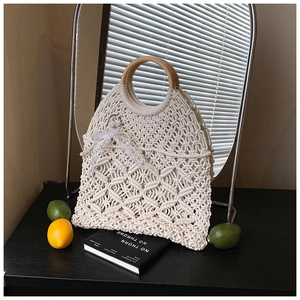 Detail of bohemian hollow knit tote bag with round wooden handles and lace bow charm