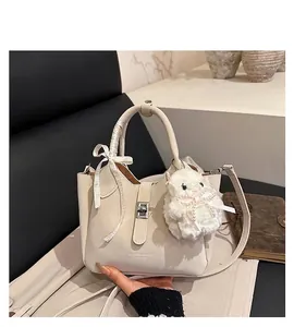 Detail of cream leather bucket bag featuring a silk scarf bow and plush charm