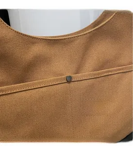 Close-up of brown heavy canvas fabric with neat stitching and metallic rivet accents