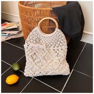 Detail view of woven beach bag showing intricate patterns, wooden handles, and lace bow