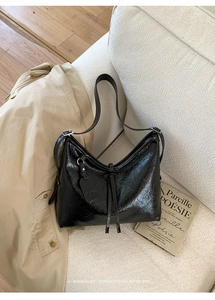 Detail of black wrinkled oil wax leather tote bag with metallic buckle and fashion tag
