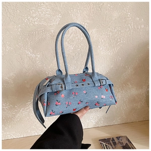 Detail of light blue denim handbag featuring pink floral pattern and silver buckle straps