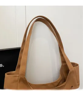 Close-up of reinforced canvas handles on a durable brown minimalist tote bag