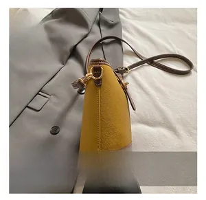 Dettaglio borsa a secchiello bicolore giallo zenzero e marrone con trama e fibbia dorata