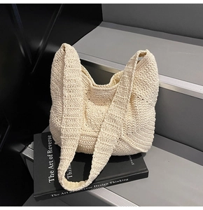 Gros plan détaillé du sac en maille crème sur un livre avec motif au crochet texturé