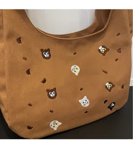 Detail of soft brown canvas tote showing textured fabric and colorful cat head embroidery