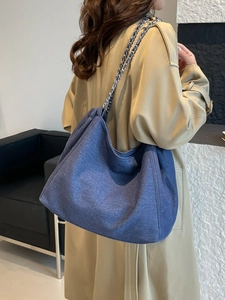 Sac hobo en denim bleu avec bandoulière chaîne argentée porté par le mannequin