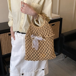 Detail of woven beach tote with intricate hollow patterns and pearl bow decoration