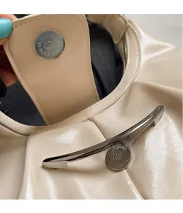 Detail of glossy beige shoulder bag featuring silver metal magnetic buckle closure