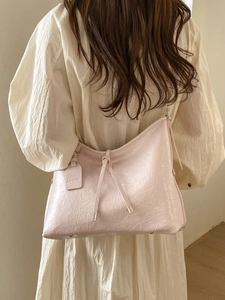 Pink oversized tote bag in pleated wax leather shown on model with tied knot detail