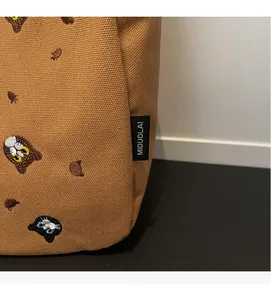 Close-up of fine cat and bear embroidery on the textured brown canvas tote bag detail