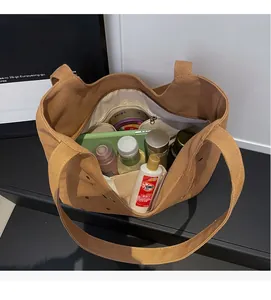 Top view of spacious interior of brown canvas tote bag with tablet and cosmetics