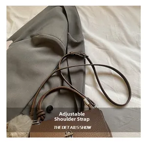 Detail of brown litchi leather bag with woven handle and adjustable strap on a blazer