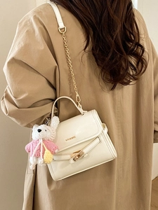 White faux leather crossbody bag with gold chain strap and cute teddy bear charm detail