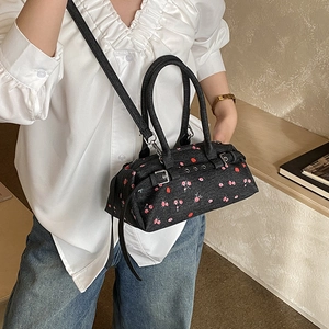 Detail of black floral Boston bag with red cherry print and adjustable strap
