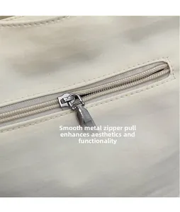 Détail de la fermeture éclair en métal argenté sur un sac seau en toile crème