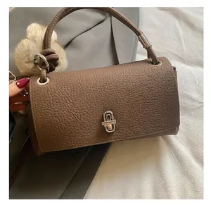 Detail of lychee pattern leather handbag with silver twist lock and plush charm accessory