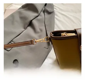 Dettaglio del moschettone dorato e delle cuciture a contrasto su una borsa in pelle