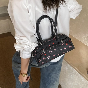 On-model view of a black denim Boston bag featuring pink floral prints and a shoulder strap