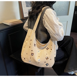 Detail of embroidered animal patterns on a large beige canvas tote bag with a label