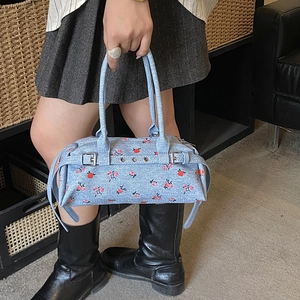 Close-up of floral denim handbag featuring red rose patterns and metallic buckle details