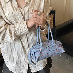 Blue denim cylindrical handbag with red floral pattern and silver metal hardware details