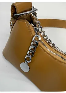 Dettaglio della borsa in pelle color cammello con catena d'argento e ciondolo lucido