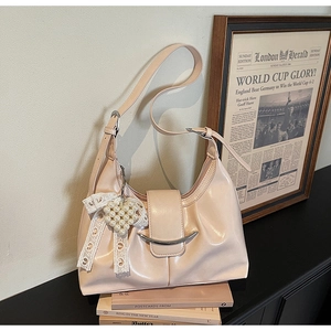 Detail of pink crescent bag with pearl heart charm on vintage book aesthetic setting