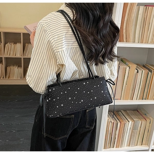 Détail du sac baguette noir minimaliste avec motifs d'étoiles et doubles fines bretelles