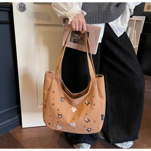 Close-up of retro brown canvas tote bag featuring detailed animal embroidery and brand tag