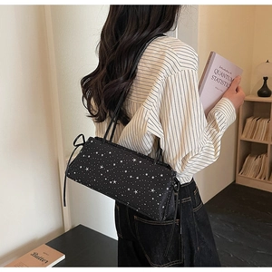 Detalle del bolso baguette negro rectangular con patrón de estrellas y correas finas