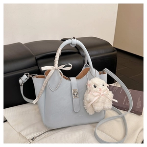 Close-up of light blue leather bucket bag with plaid ribbon and white plush sheep charm