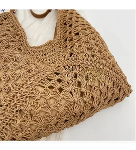Close-up of hollow crochet texture and brown leather handle on straw tote bag