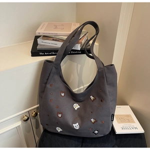 Detail of grey canvas tote bag featuring colorful cat and bear head embroidery texture