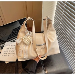 Detail of cream pleated tote bag with pearl heart charm and lace bow decoration