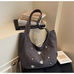 Detail of colorful cat embroidery on a dark grey canvas tote bag with wide strap