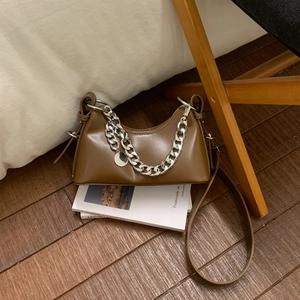 Macro shot of brown retro faux leather bag featuring double silver chain and round metal tag