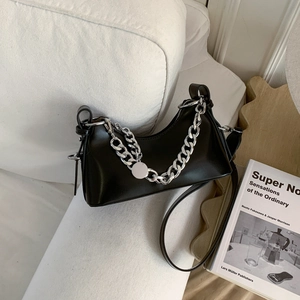 Detail of a black hobo bag with a chunky silver chain and textured leather surface