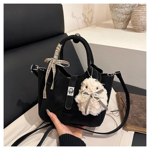 Detail of black suede handbag with silver twist lock, plaid ribbon, and plush charm