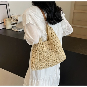 Detail of beige crochet straw tote bag with brown leather straps shown on a model
