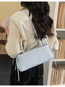Bolso baguette azul claro con diseño de estrellas y tirantes dobles en una modelo