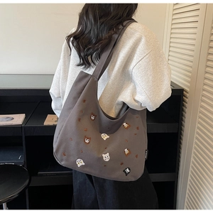 Close-up of dark grey canvas tote bag with cute cat embroidery and wide shoulder strap